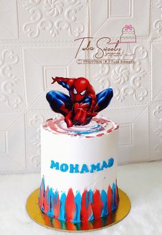 a spiderman cake with the name mohamad written on it and painted in blue, red, and yellow