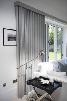 a living room with white furniture and curtains