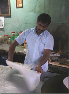 a man in a blue shirt is making something with white paper on the counter top