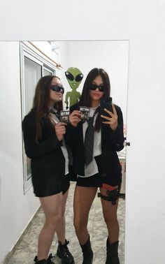 two women dressed in short shorts and high heeled boots taking a selfie