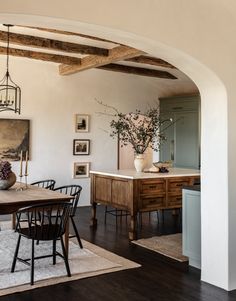 the dining room table is surrounded by black chairs and an archway leading to another room