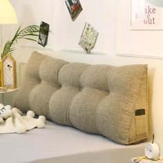 a bed with a pillow and stuffed animals on top of it next to a lamp