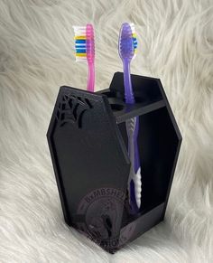 two toothbrushes sitting in a black holder on a white fur covered surface,