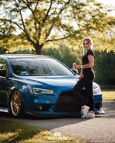 a woman standing next to a blue car