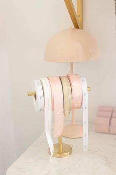 a pink lamp sitting on top of a table next to a pile of tape and a clock