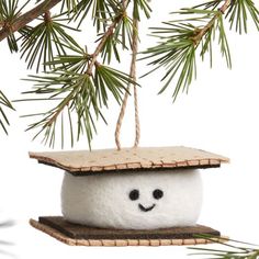 a snowman ornament hanging from a pine tree