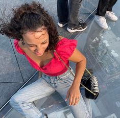 a woman standing on top of a glass floor with her mouth open and hands in the air