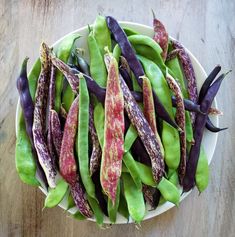 a white bowl filled with purple and green beans