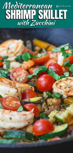 a skillet filled with shrimp, tomatoes and zucchini on top of a table