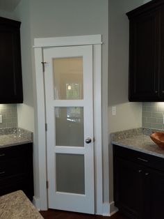 a white door in a kitchen with granite counter tops