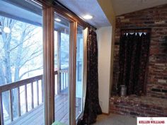 an empty room with sliding glass doors and brick fireplace in the corner, next to a balcony