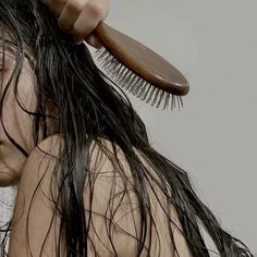 a man with long hair holding a wooden comb over his head while it's wet