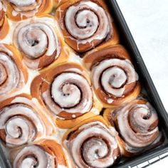 a pan filled with cinnamon rolls covered in icing