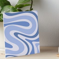 a blue and white swirl pattern art board on a table next to a potted plant