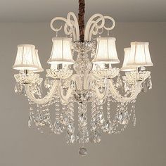 a chandelier hanging from the ceiling with four lamps on each side and two shades off