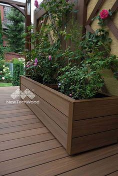 a wooden planter filled with lots of flowers on top of a hard wood floor