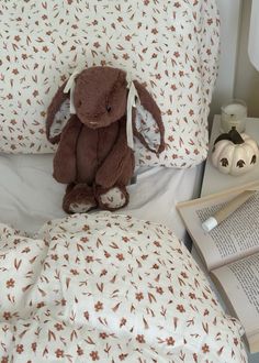 a stuffed animal sitting on top of a bed next to an open book