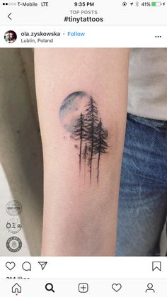 a tattoo on the arm of a woman with trees and moon in the sky behind her