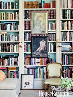 a living room with bookshelves full of different types of books and paintings on the walls