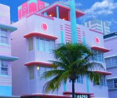 a pink and blue building with palm trees in front