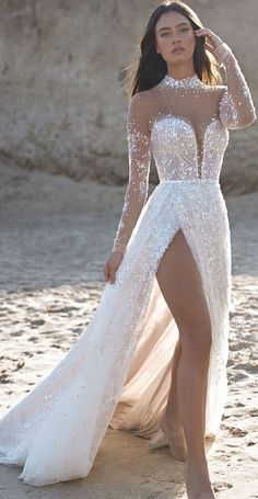 a woman standing on top of a sandy beach wearing a white dress and high heels