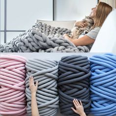 a woman laying on top of a bed covered in lots of different colored cords next to a cat