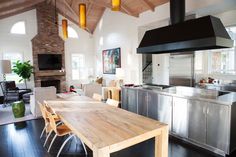 a kitchen and living room with an island in the middle, wood flooring and stainless steel appliances