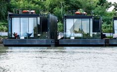 two floating houses on the water with trees in the background