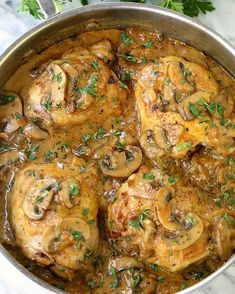 chicken with mushrooms and parsley in a pan on a marble countertop next to fresh parsley