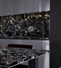 a black and white marble dining table with red chairs in front of an artistic wall