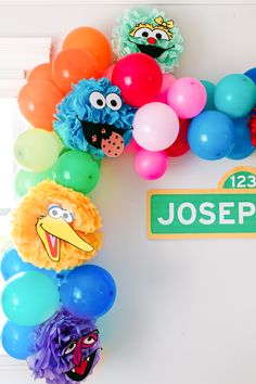 the sesame street birthday party is complete with balloon garlands, balloons and paper pom poms