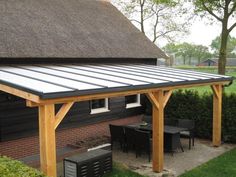 a patio covered with a metal roof next to a brick wall and green grass area