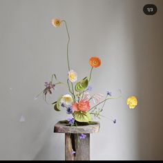 a vase filled with flowers sitting on top of a wooden table next to a white wall