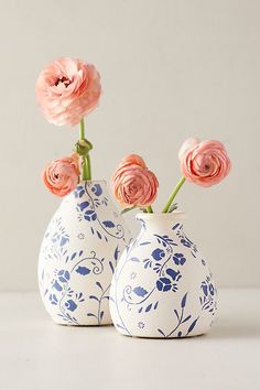 two blue and white vases with pink flowers in them