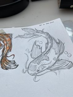 a drawing of two fish on top of a piece of paper next to a computer mouse