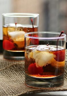 two glasses filled with ice and fruit on top of a table