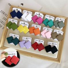 several different colors of bow ties on display in a wooden frame with white paper and black clippings