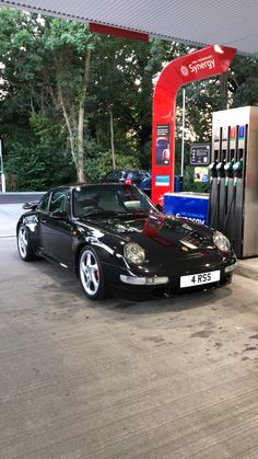 a black sports car parked at a gas station