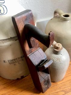 an old wooden clamper next to two white jugs