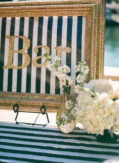 there is a vase with white flowers in it and a sign on the table that says bar b q