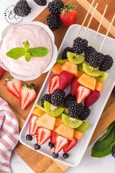 fresh fruit skewers with yogurt and mint leaves on a cutting board