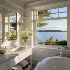 a bath room with a tub a sink and a window near the water's edge