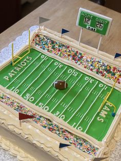 a football field cake is decorated with sprinkles and a football on top