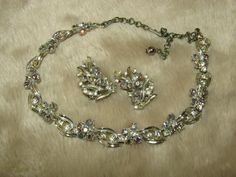 "A silver tone necklace adorned with aurora borealis rhinestones and clear rhinestones with matching earrings. Necklace is missing one clear rhinestone and the chain is heavily tarnished. Needs cleaned. Necklace measures 12.5\" long, with a 3\" extender. The earrings need to be cleaned, but are otherwise in fantastic condition. The earrings measure 1.5\" tall by 1\" wide. Clip on style. Notsigned/tagged." Silver Costume Jewelry Sets With Bling, Silver Bling Costume Jewelry Sets, Silver Rhinestone Costume Jewelry Sets, Silver Costume Jewelry Sets With Rhinestones, Rhinestone Jewelry Set, Rhinestone Jewelry, Clear Rhinestones, Aurora Borealis, Matching Earrings