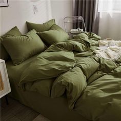 an unmade bed with green sheets and pillows