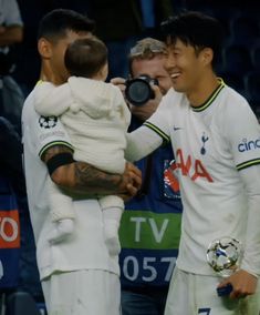 two soccer players are holding a baby in their arms