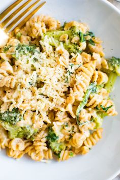 a white plate topped with pasta and broccoli covered in parmesan cheese