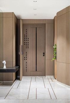 an entry way with wooden doors and tile flooring, along with a plant in the corner