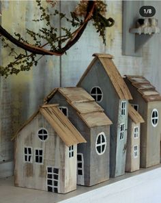 three small wooden houses sitting on top of a shelf