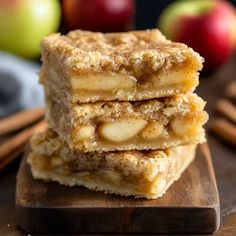 apple pie bars stacked on top of each other with cinnamon sticks and apples in the background